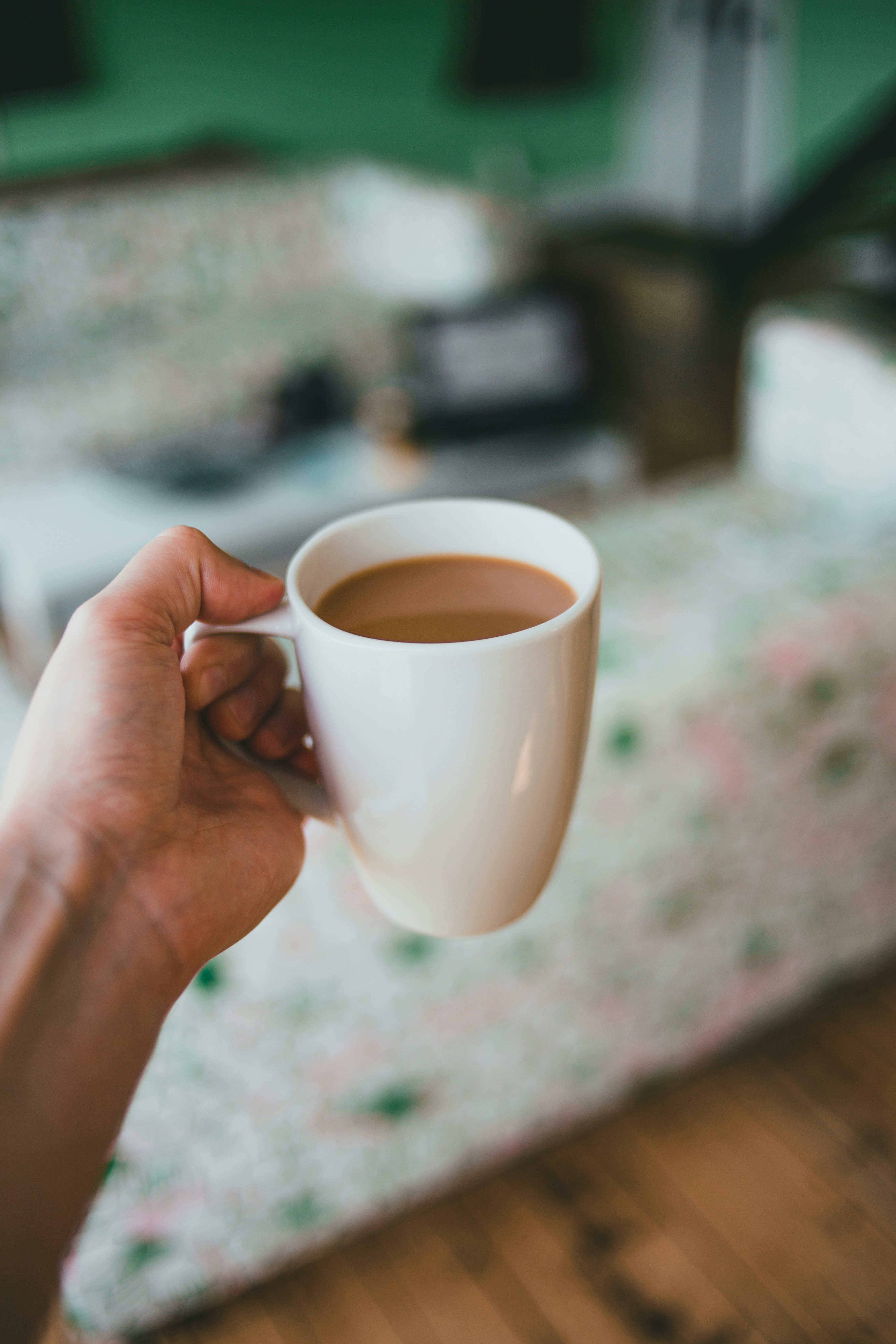 person holding white ceramic mug with brown liquid